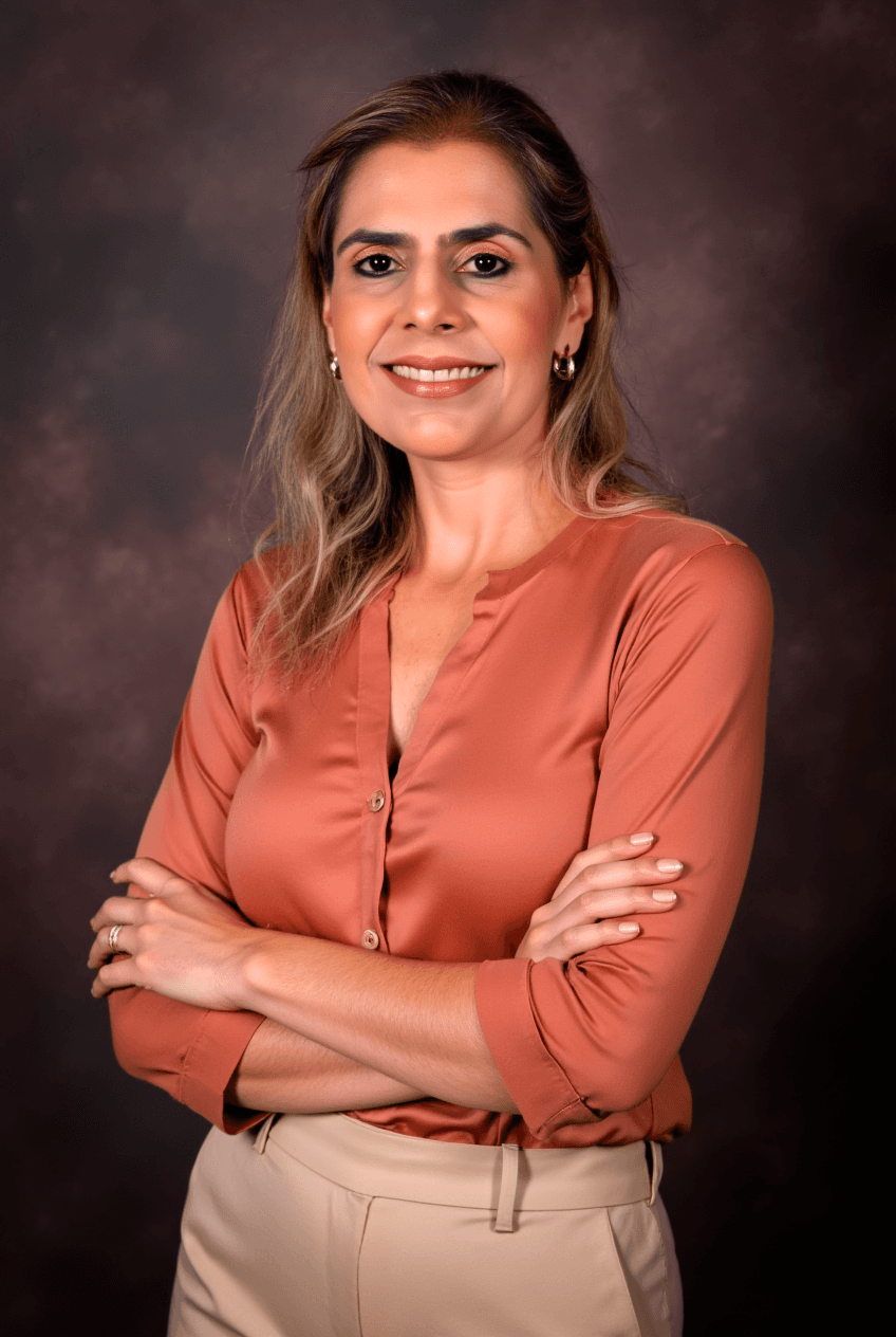 Dra. Tatiana Baruque sorrindo com os braços cruzados